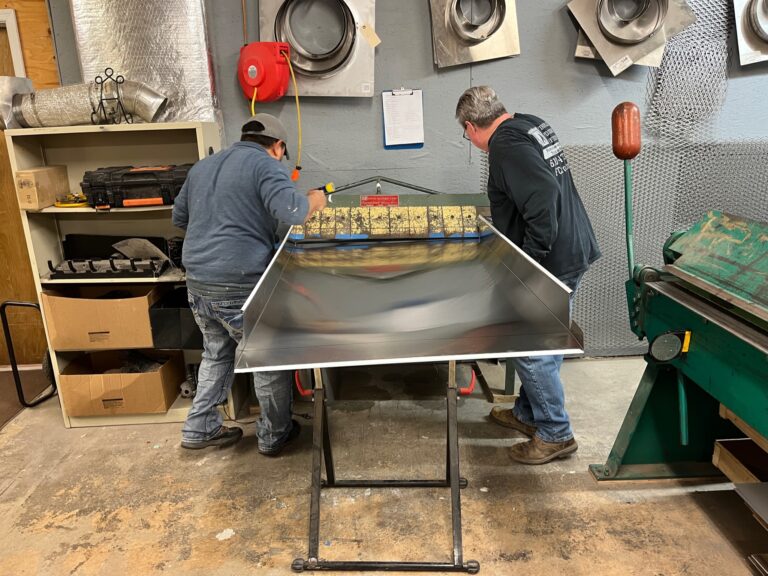 Two Chimney Cap Technicians working with piece of metal